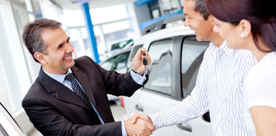 Couple buying a car and salesman handling keys